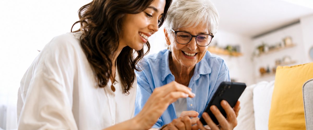 A patient booking an appointment on her phone at home, with a family member alongside.
