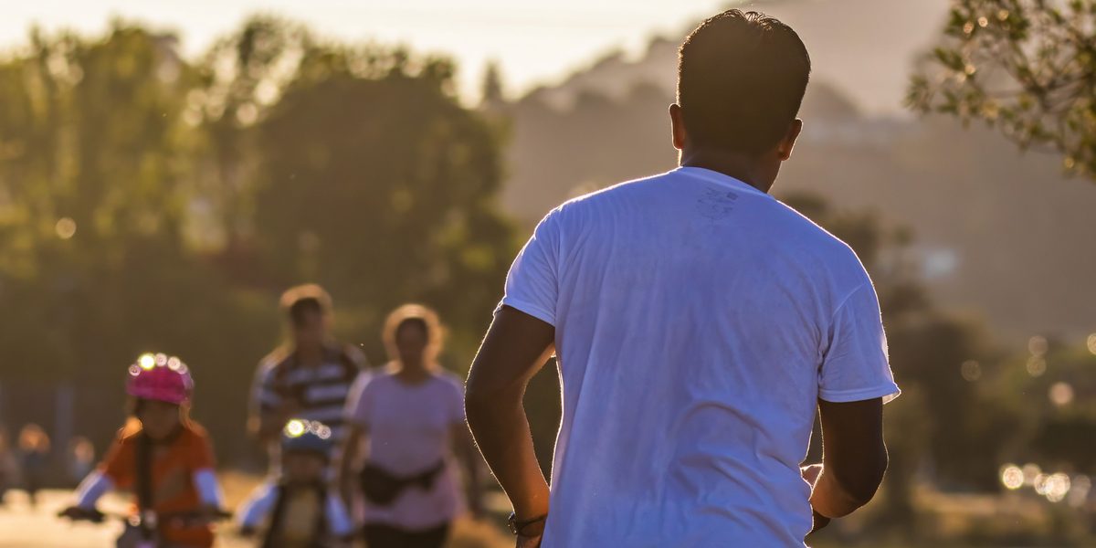 A patient jogging on a sunlit path, staying active between visits.